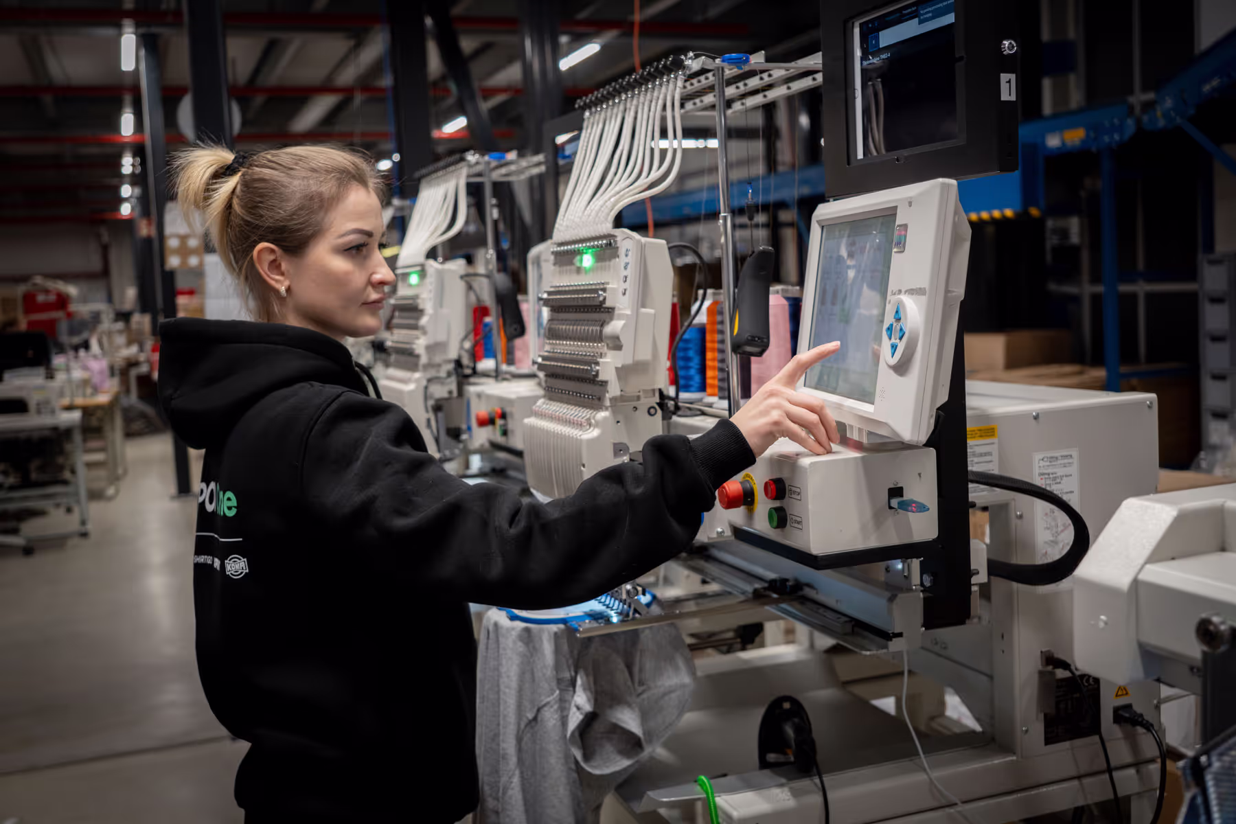 Produktionsmitarbeiterin bedient Stickmaschine
